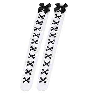 Détail de chaussettes hautes blanches avec des nœuds noirs et des motifs d'os croisés.