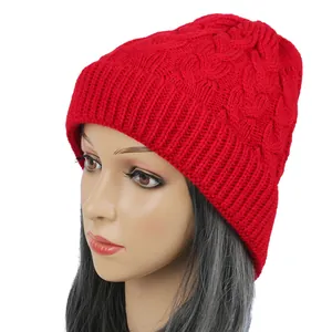 Detailed view of a red cable-knit beanie hat presented on a mannequin head model