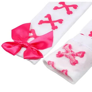 Vue détaillée de chaussettes hautes blanches avec motifs d'os roses et un nœud en satin
