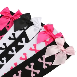 Détail de bas hauts Lolita avec nœuds en satin et motifs d'os croisés.