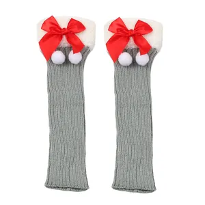 Close-up of Christmas knitted leg warmers with red bows and white pom poms