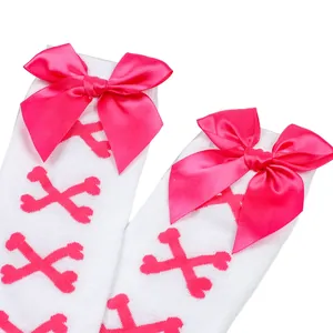 Détail de chaussettes montantes blanches avec motifs d'os roses et nœuds en satin