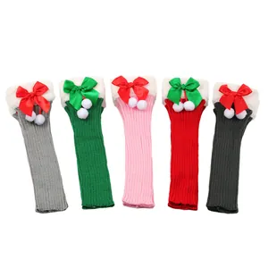 Detailed view of knitted Christmas leg warmers with bows and pom-poms in five colors