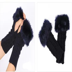 Close-up of navy blue knitted fingerless gloves showing faux fur trim and knit texture.