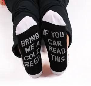 Detailed view of novelty cotton socks featuring funny 'Bring me a cold beer' text on soles