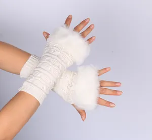 Detailed view of white knitted fingerless gloves with elegant faux fur trim worn on hands