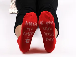 Detailed view of red cotton socks with funny 'bring me coffee' text on the soles