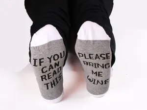 Close-up detail of novelty cotton socks with 'Bring Me Wine' text print on the soles