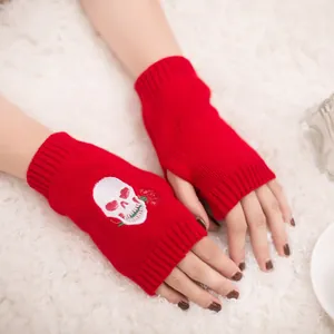 Dettaglio di guanti senza dita in maglia rossa con ricamo di teschio e rosa per inverno.