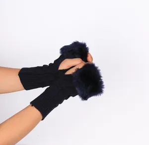 Close-up detail of navy blue knitted fingerless gloves featuring plush faux fur trim on hands