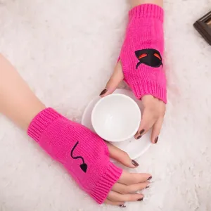 Close-up detail of bright pink knitted fingerless gloves featuring black devil embroidery