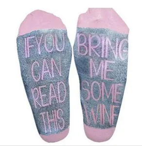 Close-up view of pink and grey socks with Bring Me Some Wine text on the soles.
