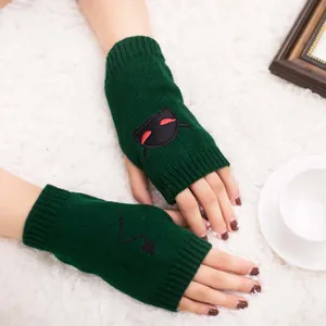 Close-up of green knitted fingerless gloves with unique devil embroidery for Halloween
