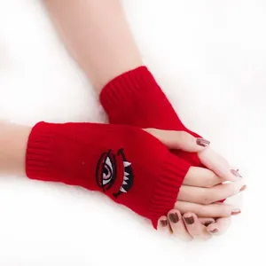 Detailansicht roter gestrickter fingerloser Handschuhe mit Teufelsaugen-Stickerei-Motiv.