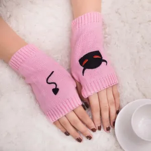 Close-up of pink knitted fingerless gloves with devil face and tail embroidery details
