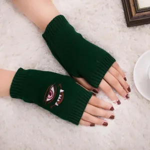 Nahaufnahme von Harajuku-Stickerei mit Auge und Zähnen auf grünen Handschuhen.