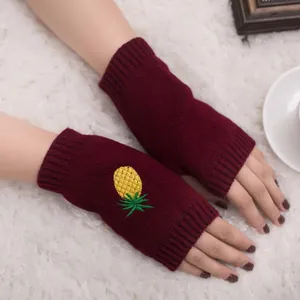Gros plan de mitaines en tricot bordeaux avec broderie d'ananas jaune