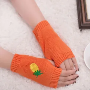 Gros plan de mitaines en tricot orange avec motif d'ananas brodé