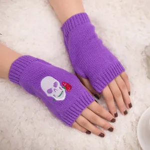 Dettaglio guanti senza dita in maglia viola con ricamo a teschio e rosa rossa.