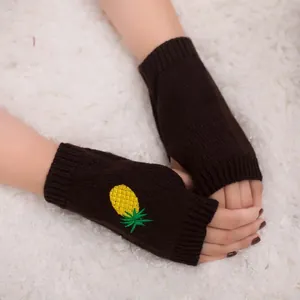 Gros plan de gants en tricot sans doigts foncés avec une broderie d'ananas jaune vif.