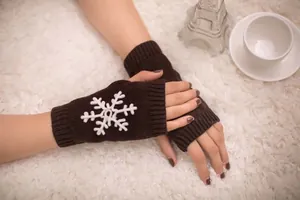 Close-up of brown knitted fingerless gloves with white snowflake pattern embroidery