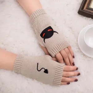 Detail view of beige knitted fingerless gloves with devil embroidery for Halloween