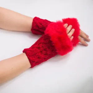 Détail de gants rouges tricotés sans doigts avec bordure en fausse fourrure et motif de losanges.