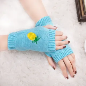 Gros plan sur des mitaines en tricot bleu clair avec une broderie d'ananas jaune