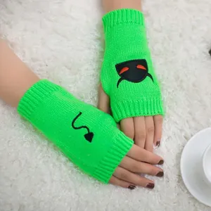 Close-up detail of neon green knit fingerless gloves with black devil embroidery.