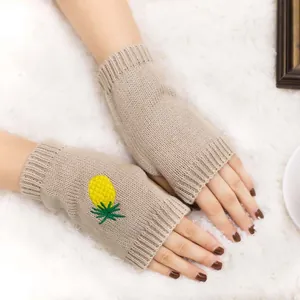 Gros plan détaillé sur les mitaines en tricot kaki avec broderie ananas jaune vif
