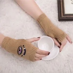 Detailansicht der Teufelsaugen-Stickerei auf khakifarbenen fingerlosen Strickhandschuhen