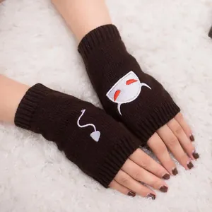 Detailed view of white devil embroidery on brown knitted fingerless gloves