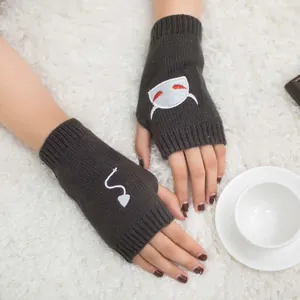 Close-up of grey knitted fingerless gloves with white devil embroidery on white fur.