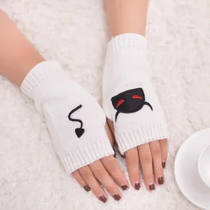 Close-up of white knitted fingerless gloves with devil embroidery motifs.