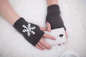 Macro view of knitted fingerless gloves with snowflake embroidery while holding a phone