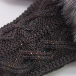 Gros plan d'un gant sans doigts en maille torsadée foncée avec fil pailleté et bordure en fourrure