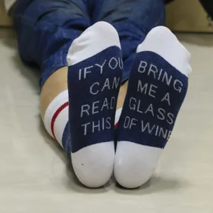 Close-up of cotton socks with Bring me a glass of wine novelty text on the soles.