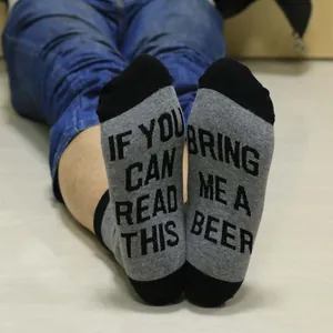 Close-up of funny beer-themed text on the sole of grey and black cotton crew socks