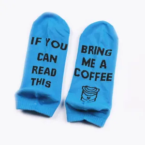 Close-up of blue cotton socks featuring humorous 'Bring me a coffee' printed soles