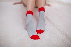 Detailed close-up view of grey and red cotton mid-calf socks on a white furry rug