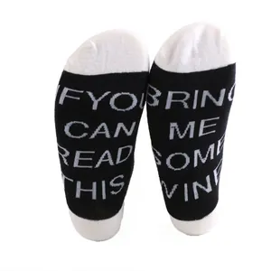 Detail view of woven 'Bring Me Some Wine' message on black and white ankle socks.