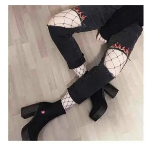 Fashionable black fishnet stockings for women styled with ripped jeans and platform boots