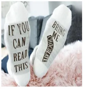 Detailed view of white mid-tube cotton socks with funny chocolate letter print on soles.