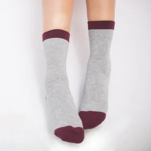 Close-up detail of grey mid-calf unisex cotton socks with burgundy cuffs worn on feet
