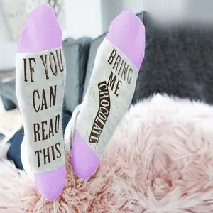 Close-up detail of cozy grey and purple socks featuring funny 'Bring Me Chocolate' printed text