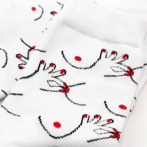 Dettaglio macro di calzini bianchi con illustrazione minimalista di mano e seno in rosso e nero