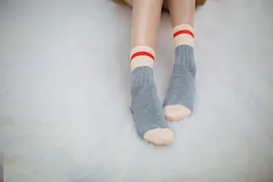 Detailed view of grey cotton mid-calf socks featuring a red stripe and beige toe and heel