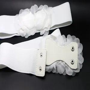 Close-up of white elastic waist belt with large 3D flower decoration and snap button