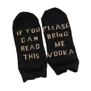 Macro view of black cotton ankle socks with knitted 'BRING ME VODKA' text on the sole.