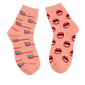 Detailansicht von pfirsichfarbenen Baumwollsocken mit Lippen- und Zahnbürstenillustration.